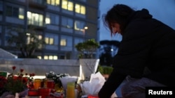 A woman places a candle at the statue of late Pope John Paul II at the Gemelli Hospital, where Pope Francis is being treated for pneumonia, in Rome, March 12, 2025. 