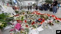 在德国杜塞尔多夫机场乘客们注视着为坠机罹难者敬献的蜡烛和鲜花。