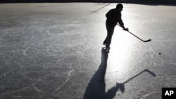 A skater plays ice hockey on a frozen lake in Beijing December 23, 2010.