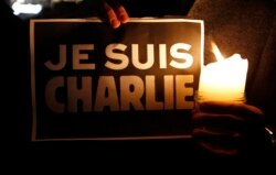 FILE - A person holds a candle in front a placard that reads "I am Charlie" to pay tribute during a gathering in Strasbourg following a shooting by gunmen at offices of the weekly satirical magazine Charlie Hebdo in Paris, Jan. 7, 2015.