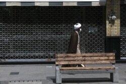 A cleric walks past a closed shop of Tehran's Grand Bazaar, Iran, Apr. 10, 2021. Iran on Saturday imposed partial lockdown on businesses in major shopping centers as well as intercity travels through personal cars in major cities.