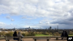 People sit on benches at Primrose Hill, in London, Sunday, March 29, 2020. The public have been asked to self isolate, keeping distant from others to limit the spread of the contagious COVID-19 coronavirus.