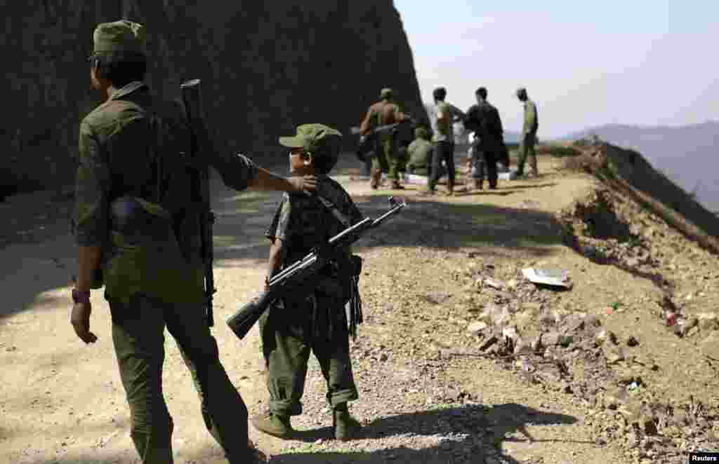 A 15-year-old soldier (2nd L) stands next to other rebel soldiers of the Myanmar National Democratic Alliance Army (MNDAA) as they guard near a military base in Kokang region March 12, 2015. Fighting broke out last month between Myanmar&#39;s army and MNDAA, which groups remnants of the Communist Party of Burma, a powerful Chinese-backed guerrilla force that battled Myanmar&#39;s government before splintering in 1989.