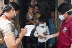 Community health volunteers check the pulse of a resident during a check-up campaign for the COVID-19 in Mumbai, India, Oct. 3, 2020.