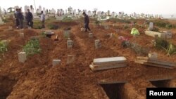 Residents look at fresh graves of people killed by what activists said were missiles fired by a Syrian Air Force fighter jet at a bakery in Halfaya, near Hama, Syria, December 24, 2012.