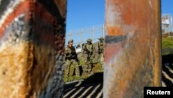 Agents with the U.S. Border Patrol Tactical Unit stand guard behind the border fence between Mexico and the United States, as seen from Tijuana, Mexico, Nov. 14, 2018. 