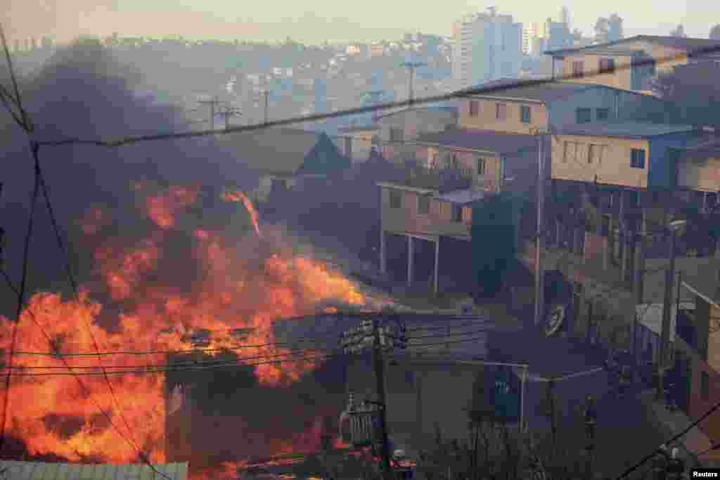 Os bombeiros tentam parar as chamas que devastam vários bairros nas colinas de Valparaiso, Chile, Abril 13, 2014.