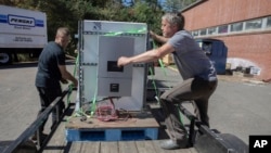 Henry Kovacs, left, and Hayden Wilson, right, volunteers with the Footprint Project, load two Tesla Powerwall batteries to deliver to communities impacted by Hurricane Helene in Mars Hill, N.C. on Oct. 9, 2024.