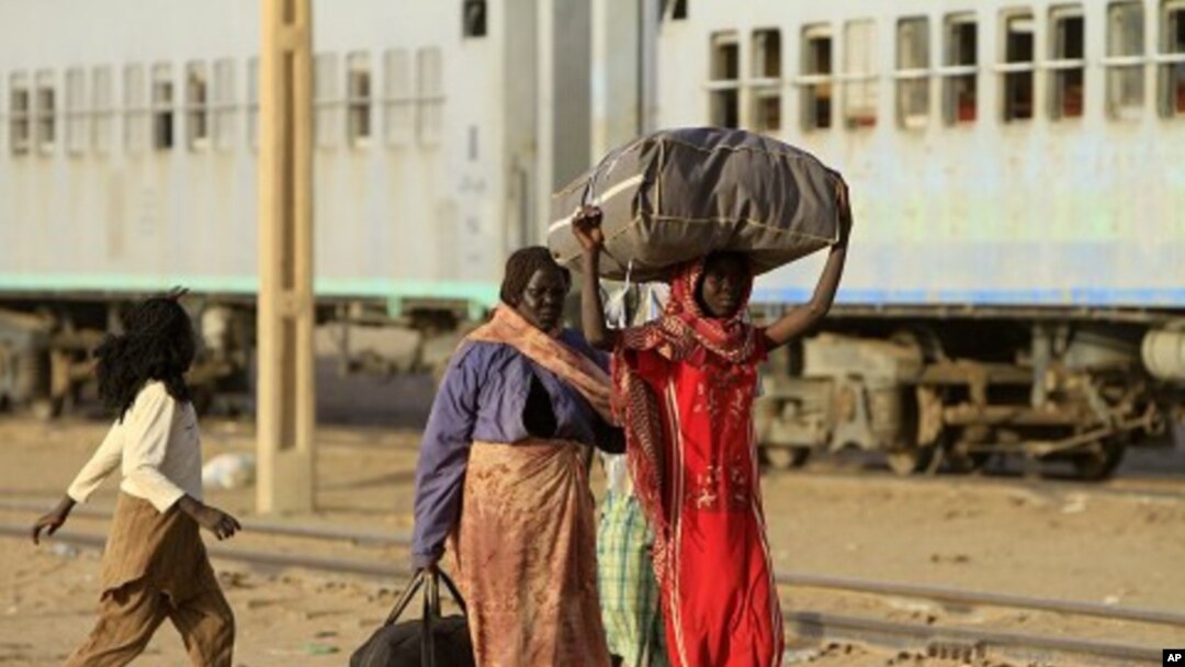 Southern Sudanese family walks towards a train to be transported back to Baher Al Gazal State in South Sudan, in Khartoum, 09 Jan 2011.