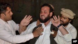 People comfort a man mourning the death of his relative, who was killed by gunmen when they hijacked two buses at a local hospital in Quetta, Pakistan, May 30, 2015. 