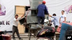 FILE - Workers remove air ducts made from aluminum sheet metal in Beijing, China.