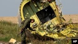 FILE - A pro-Russian rebel touches the MH17 wreckage at the crash site of Malaysia Airlines Flight 17, near the village of Hrabove, eastern Ukraine, on July 22, 2014.