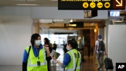 Dua pekerja di bandara internasional Seattle-Tacoma, negara bagian Washington, AS mengenakan masker di tengah perebekan virus corona di sana.