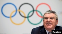 FILE - The Olympic rings are seen behind IOC President Thomas Bach at a news conference in Monaco, Dec. 6, 2014.