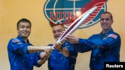 Para awak Stasiun Antariksa Internasional (ISS), dari kiri ke kanan, astronot Jepang Koichi Wakata, kosmonot Rusia Mikhail Tyurin dan astronot Amerika Rick Mastracchio, memegang obor Olimpiade Musim Dingin Sochi 2014 (6/11). (Reuters/Shamil Zhumatov)