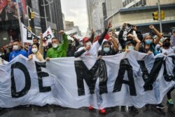Partidarios progubernamentales protestan contra las sanciones impuestas por Estados Unidos, durante conmemoración del Día Internacional de los Trabajadores, en Caracas, Venezuela, en un lluvioso sábado 1 de mayo de 2021.