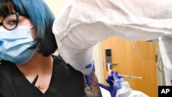 Nurse Kathe Olmstead, right, gives volunteer Melissa Harting, an injection developed by NIH and Moderna Inc., July 27, 2020, in Binghamton, N.Y.