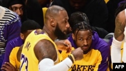 Los Angeles Lakers' guard Bronny James, center, watches father LeBron James in the NBA game season opener between the Lakers and the Minnesota Timberwolves at Crypto Arena in Los Angeles on October 22, 2024. They are the first father and son to play together in an NBA game. 