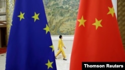 资料照：一位宾馆服务员走过欧盟和中国旗帜。彼时的欧盟和中国正在北京筹备举办欧盟-中国高级经济对话会。