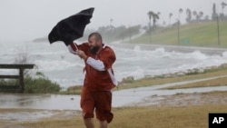 Matt Looingvill struggles with his umbrella as he tries to walk in the wind and rain, Aug. 25, 2017, in Corpus Christi, Texas.