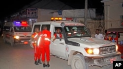 Medical workers wait by ambulances ready to transport wounded, after a bomb attack at an ice cream shop in Mogadishu, Somalia, Nov. 27, 2020. A local official said a suicide bombing at an ice cream shop in Somalia's capital killed at least seven.