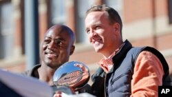 Denver Broncos quarterback Peyton Manning and defensive end DeMarcus Ware hold the Lombardi Trophy during a parade for the NFL football Super Bowl champions in Denver, Feb. 9, 2016.