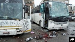 A photo released by the Syrian official news agency SANA shows blood-soaked streets and several damaged buses in a parking lot at the site of twin explosions in Damascus, Syria, March 11, 2017.
