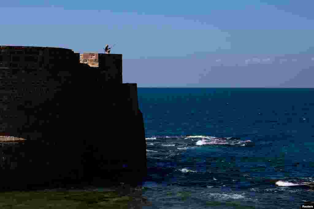 A man fishes by the Mediterranean Sea in Acre, in northern Israel.