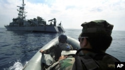 Des ingénieurs à bord d’un canot gonflable s’approchent du patrouilleur américain, l'USS Thunderbolt, dans la mer Adriatique, 13 juin 2000.