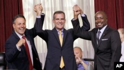 Los Angeles Councilman Joe Buscaino, left, with Los Angeles Mayor Eric Garcetti, center, and Councilman Marqueece Harris-Dawson celebrate after a city council vote, Sept. 1, 2015 in Los Angeles.