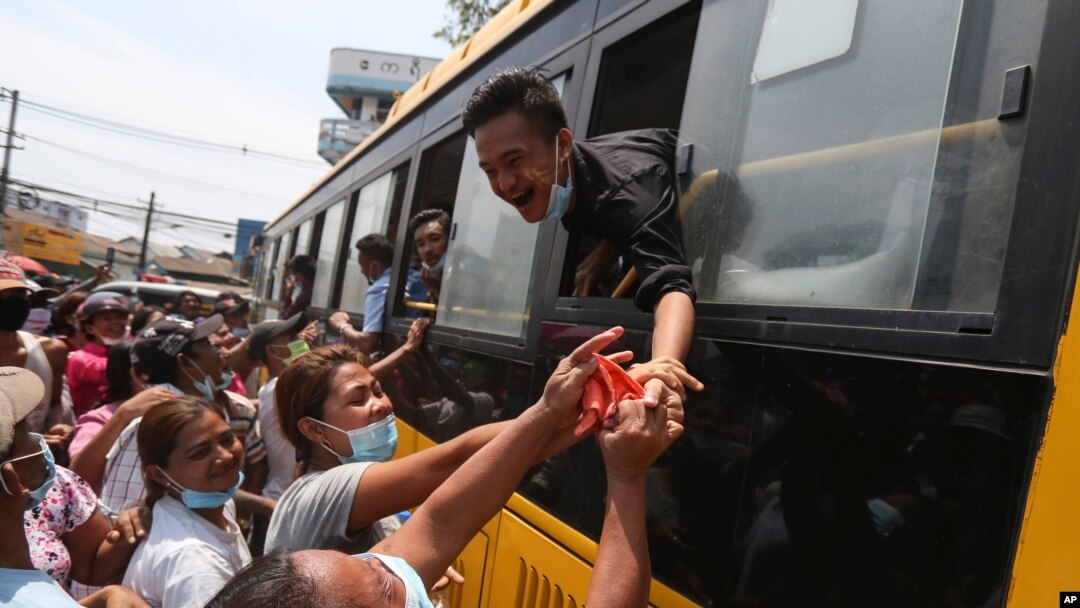 Seorang narapidana berupaya menyalami keluarganya dari dalam bus, setelah dibebaskan dari penjara Insein di Yangon, Myanmar, 17 April 2020.