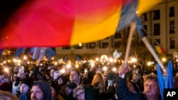 People hold cellphones with flashlights during a pro-European rally ahead of the Dec. 8 runoff presidential elections in Bucharest, Romania, Dec. 5, 2024.