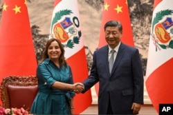 FILE - China's President Xi Jinping, right and Peru's President Dina Boluarte shake hands during a signing ceremony at the Great Hall of the People in Beijing, June 28, 2024.