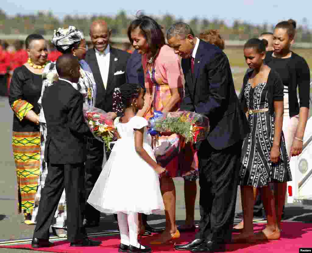 U.S. President Barack Obama and first lady Michelle Obama receive flowers, as their daughter Sasha (2nd R) watches, during an official arrival ceremony at Julius Nyerere Airport in Dar es Salaam, Tanzania, July 1, 2013. REUTERS/Jason Reed (TANZANIA - Tag