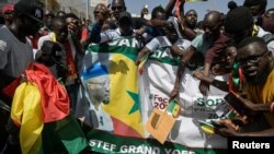 FILE - Supporters of detained Senegalese opposition leader Ousmane Sonko hold a banner during a march to protest against the postponement of the presidential election that was scheduled for February 25 in Dakar, Senegal February 17, 2024.