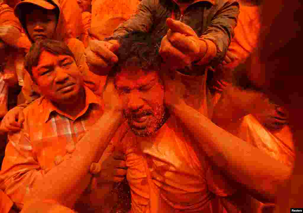 A devotee is smeared with vermilion powder to welcome the arrival of spring and Nepali New Year, at Thimi, in Bhaktapur.