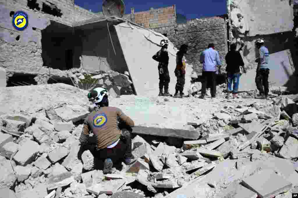 This photo provided by the Syrian Civil Defense group known as the White Helmets, shows members of Civil Defense inspecting damaged buildings after airstrikes hit the Bustan al-Qasr neighborhood of Aleppo, Sept. 25, 2016.