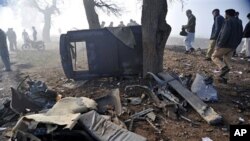 Pakistani officials examine a remains of the police vehicle damaged by a roadside bomb on the outskirts of Peshawar, Pakistan, February 8, 2011