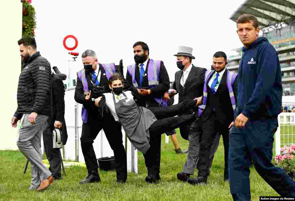An extinction rebellion protester is escorted from the racecourse during the Royal Ascot horse race in Ascot, England, June 19, 2021. (Action Images)