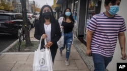 FILE - Emili Prado, 21, left, Christine Cuenca, 18, and Jason Jimenez, 19, campaign to turn out the vote in the largely Hispanic community of Port Richmond in Staten Island, N.Y., Oct. 23, 2020. 