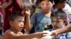 In this Nov. 19, 2014 photo, a boy receives rice from a novice Buddhist monk near Mahar Aung Myae monastery in Hlaing Thaya, northwest of Yangon, Myanmar. Monks in the desperately poor neighborhood combine whatever food they received during morning alms into a giant pot and redistribute it to the less fortunate. 