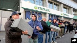 Volunteers of the Azov Civil Corps pass stones to each other to build a wall in front of the central branch of Russian Sberbank during a protest in Kyiv, Ukraine, March, 13, 2017.