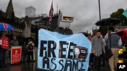 A supporter of Julian Assange protests outside the Houses of Parliament, in London, Monday, Oct. 21, 2019.