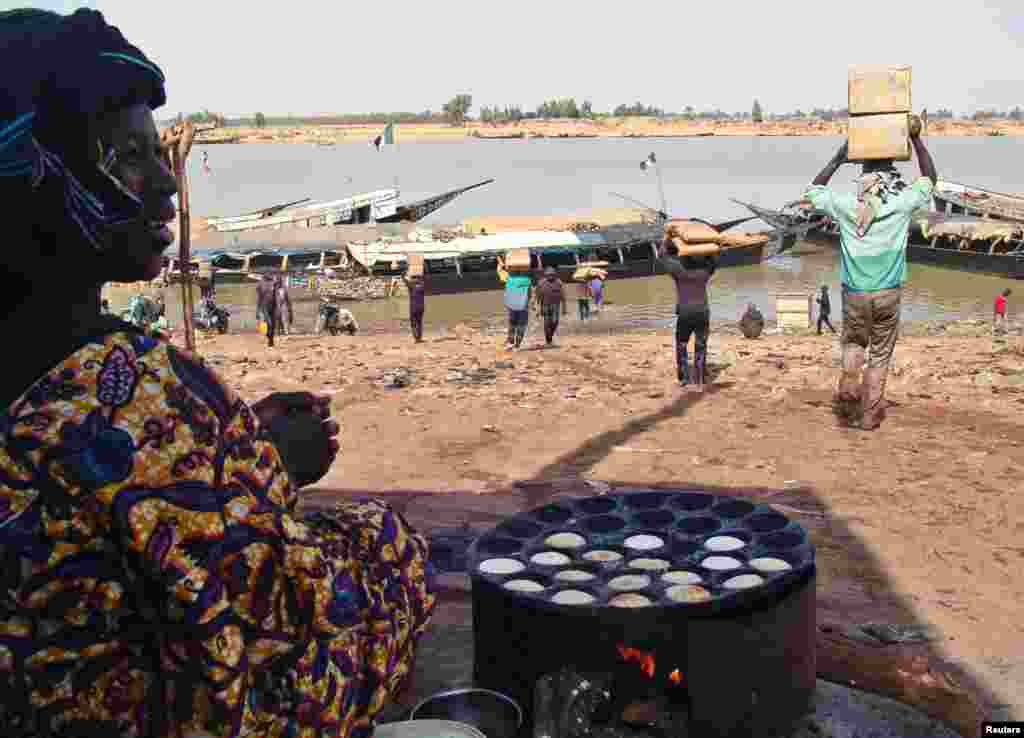 A Malian woman looks at men carrying humanitarian food aid, Mopti, Mali, February 4, 2013.