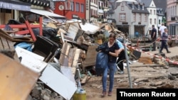 A woman carries a bag in an area affected by floods caused by heavy rainfalls in Bad Muenstereifel, Germany, July 19, 2021.