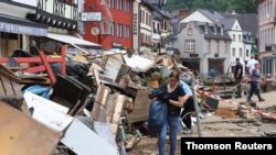 A woman carries a bag in an area affected by floods caused by heavy rainfalls in Bad Muenstereifel, Germany, July 19, 2021.