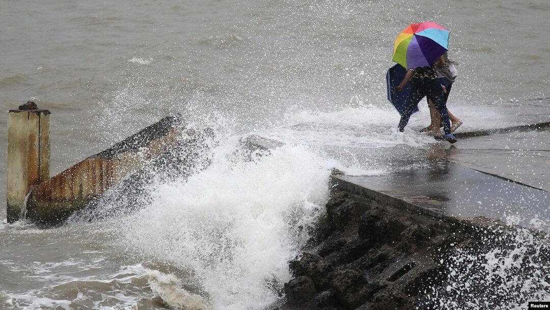 People move away as waves caused by Typhoon Utor crash on a seawall in Haikou, Hainan province, China, Aug. 14, 2013.