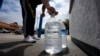 Seorang pria menutup botol yang baru diisi air minum di Irving, Texas, 22 Maret 2024. (Foto: LM Otero/AP Photo)