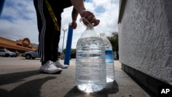 Seorang pria menutup botol yang baru diisi air minum di Irving, Texas, 22 Maret 2024. (Foto: LM Otero/AP Photo)