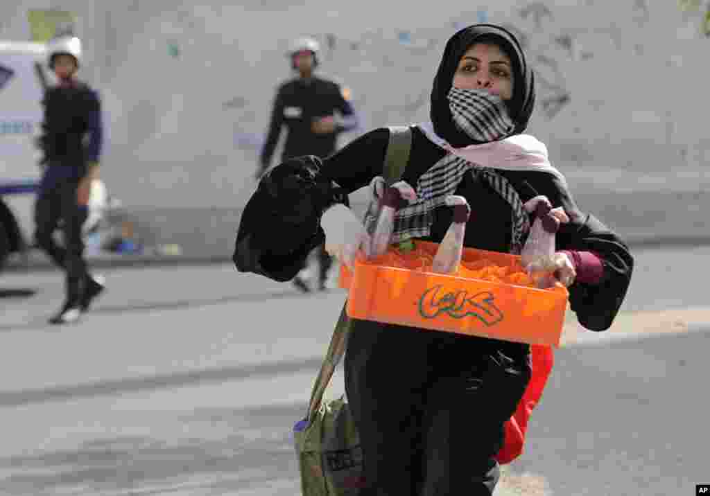 An anti-government protester picks up and runs with a crate of Molotov cocktails that other protesters abandoned when police arrive in Sanabis. (AP)